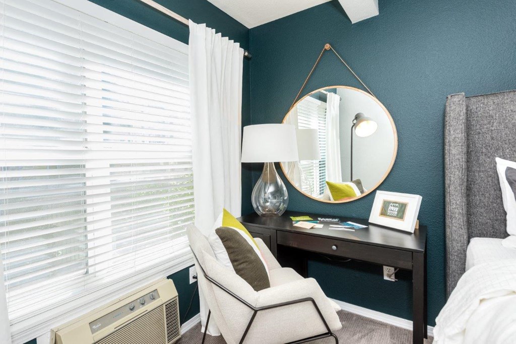 a bedroom with a chair and a desk with a mirror
