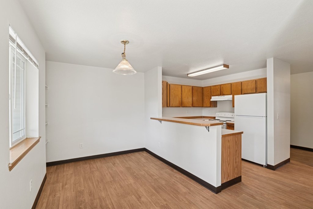 A kitchen with white appliances and wooden cabinets.