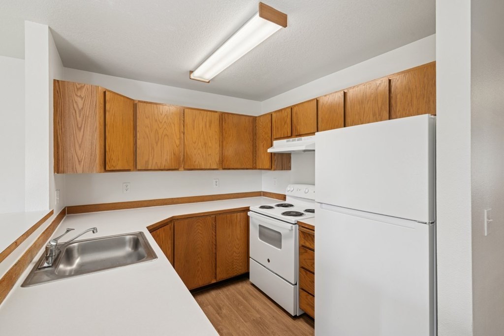 A kitchen with white appliances and wooden cabinets.