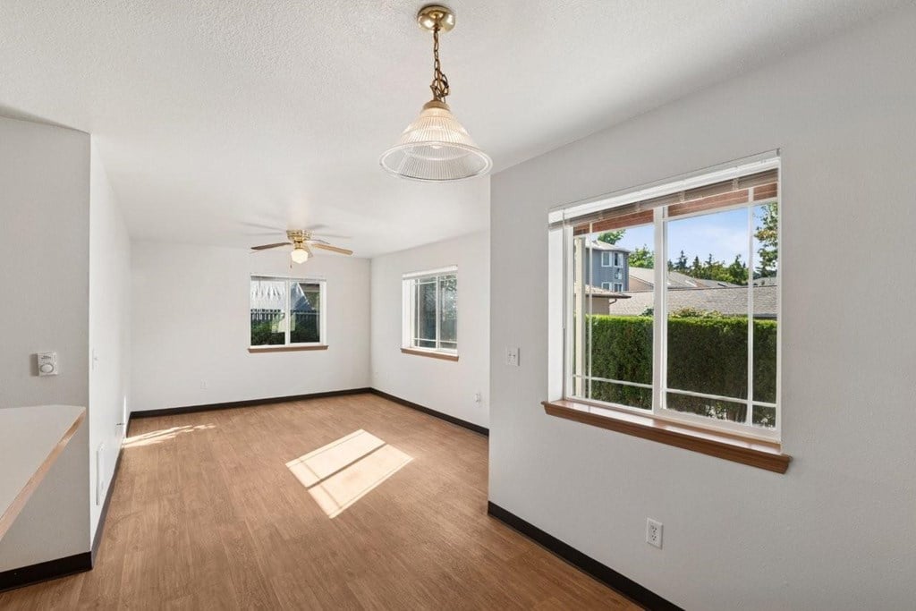 A room with a ceiling fan and a window with a view of a house.