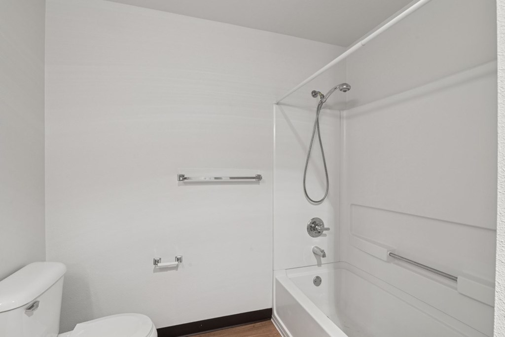 A white bathroom with a toilet, tub, and shower.