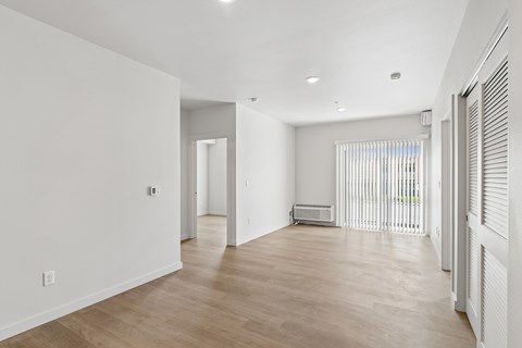 A spacious room with wooden flooring and white walls.