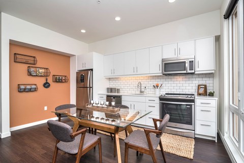 A kitchen with a table and chairs in front of it.