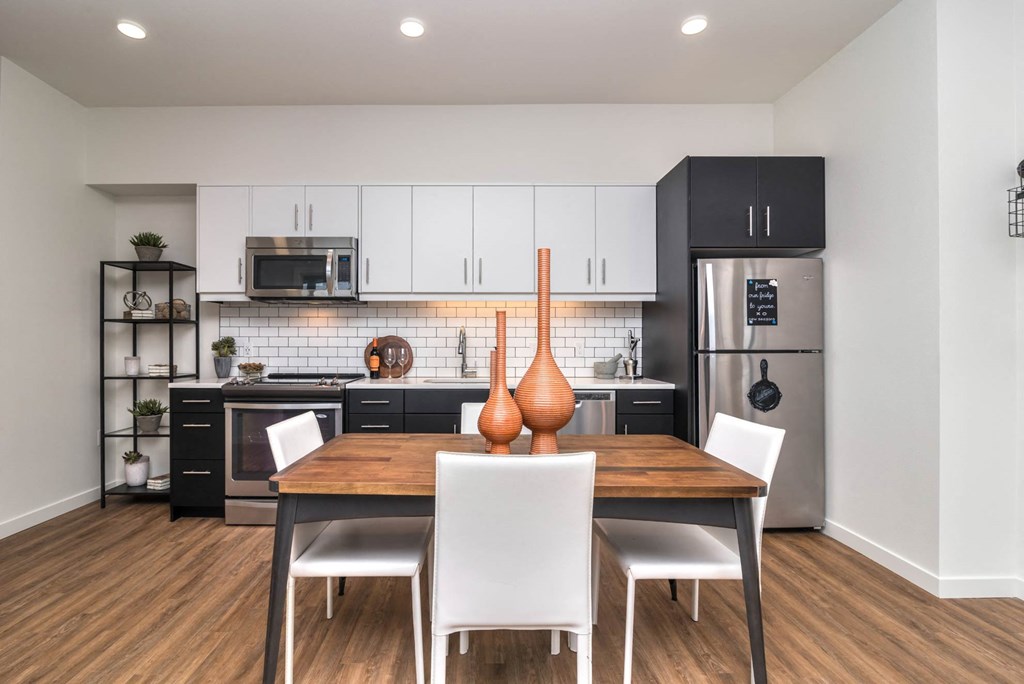 an open kitchen and dining area with a wooden table and white chairs