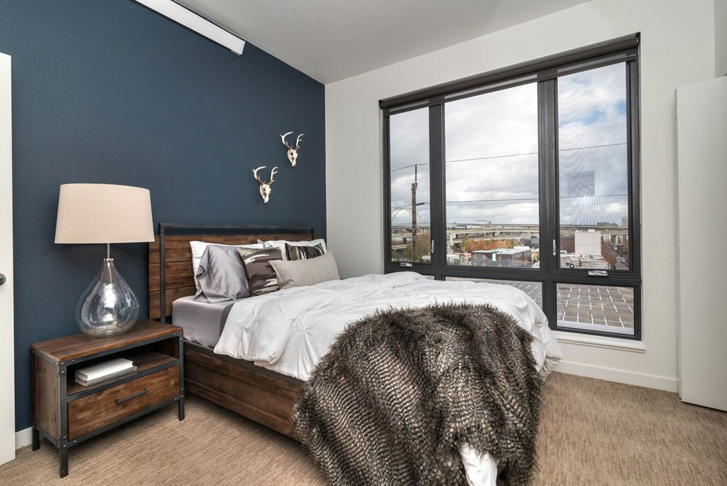 a bedroom with a large window and a bed with a wooden headboard