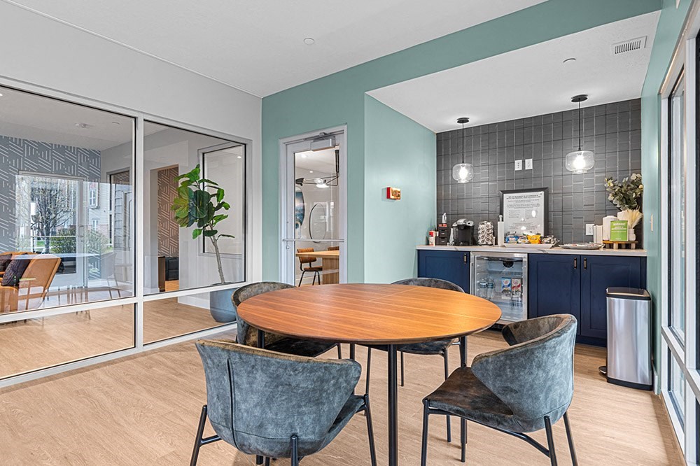 a dining area with a table and chairs and a kitchen in the background