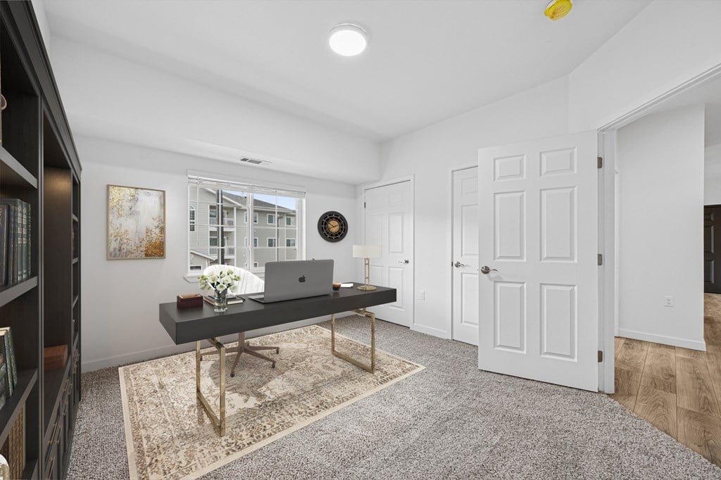 A room with a laptop on a desk and a clock on the wall.