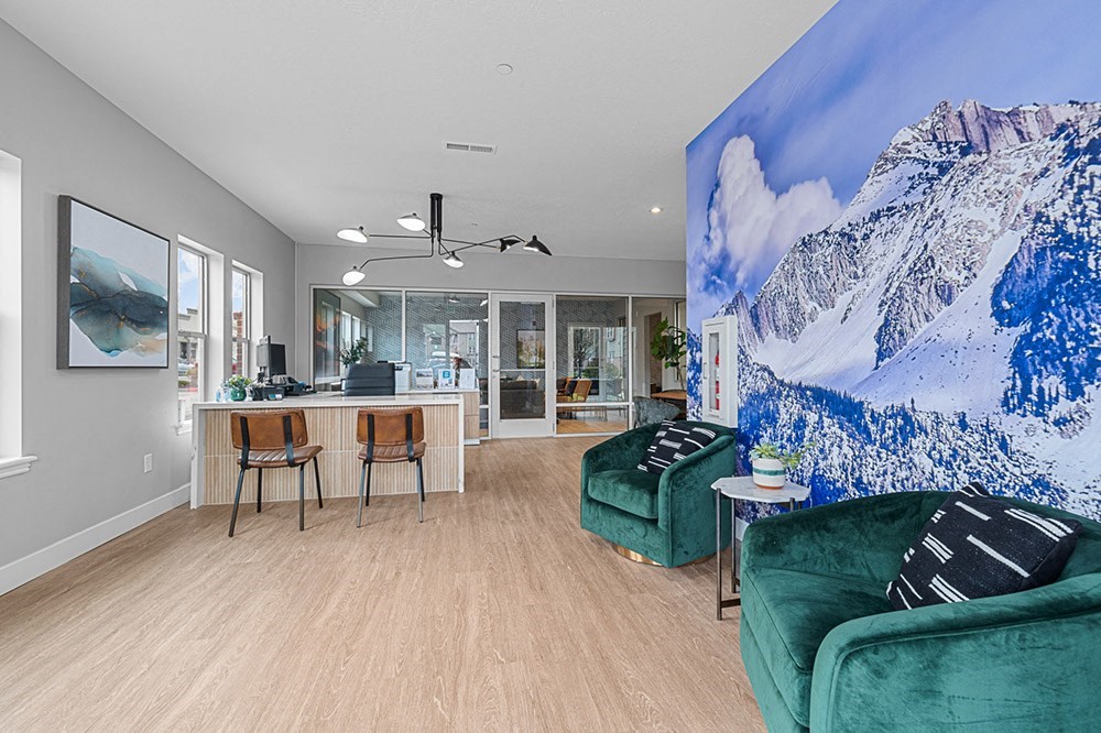 a living room with a large painting of a mountain on the wall and two green couches