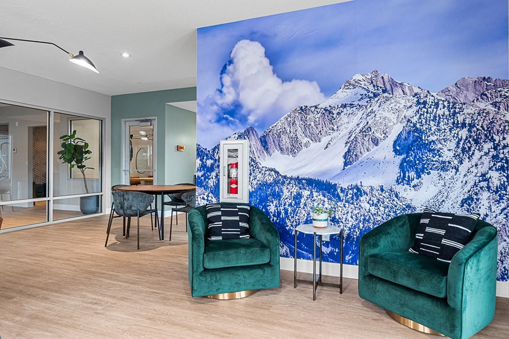 a room with two green chairs and a large mural of a snowy mountain on the wall