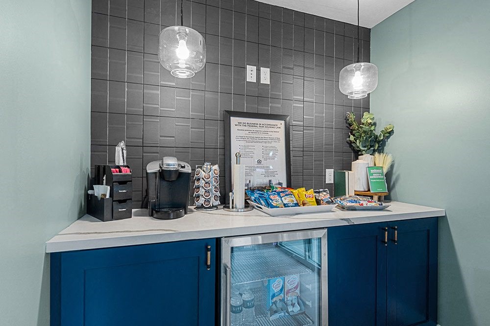 a coffee bar with blue cabinets and a white counter top with a coffeemaker and coffee