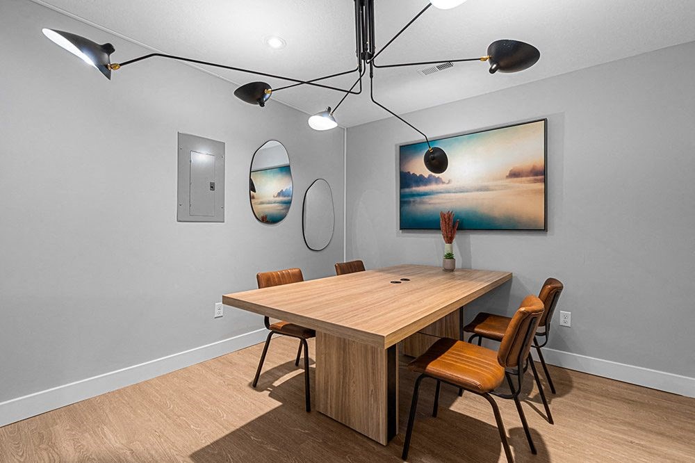 a dining room with a table and chairs and a painting on the wall