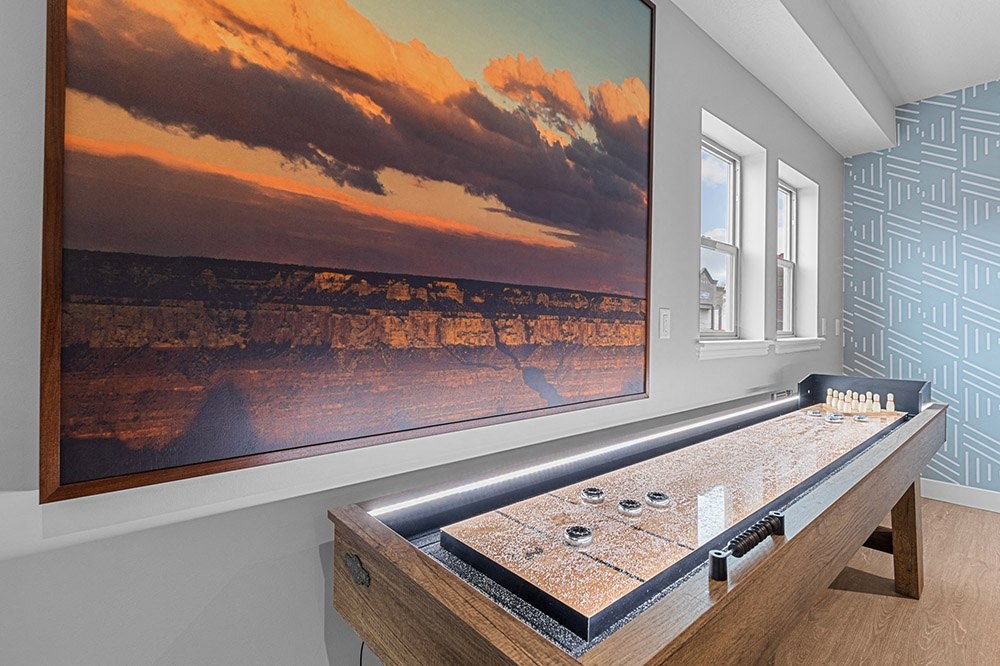 a game room with a large screen tv and a shuffleboard table