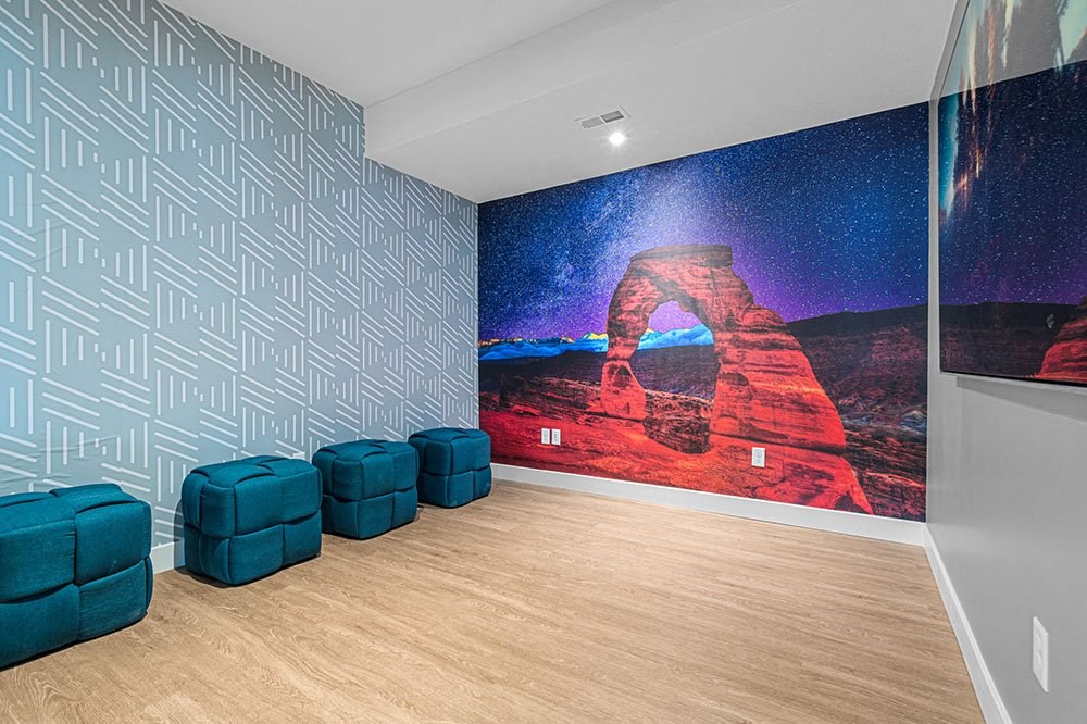 a room with two blue chairs and a large painting on the wall