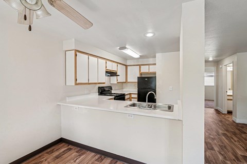 A kitchen with white cabinets and a wooden floor.