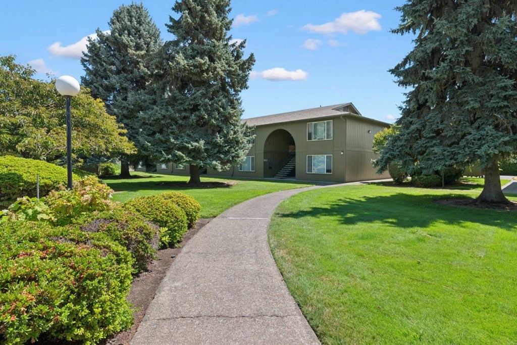 A pathway leads to a building with a green lawn on either side.