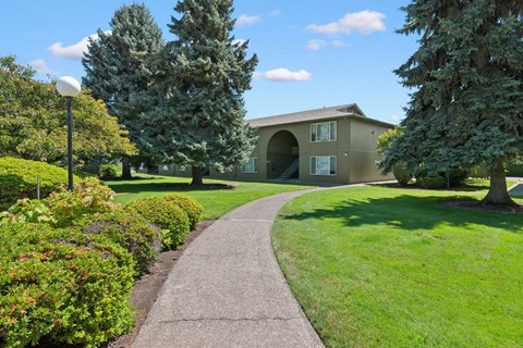 A pathway leads to a building with a green lawn on either side.