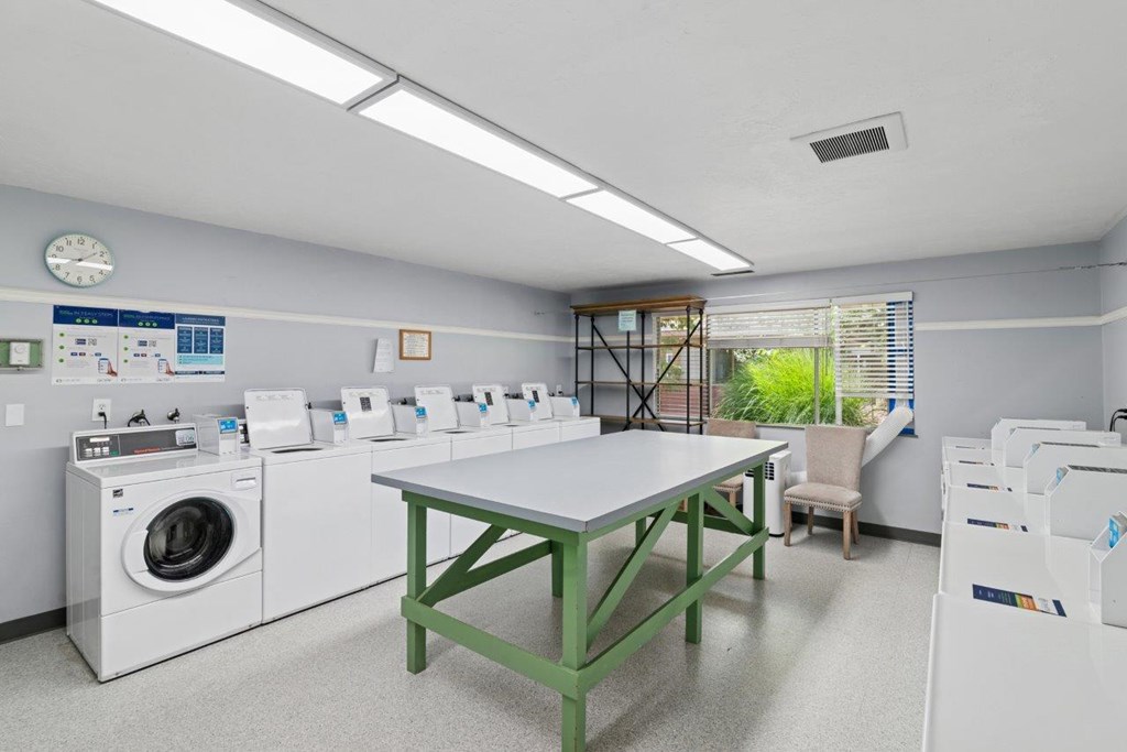 A laundry room with a table, chairs, and washing machines.