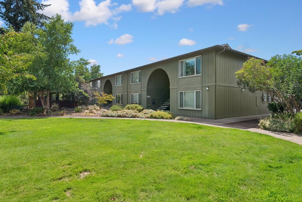 A green lawn in front of a grey building.