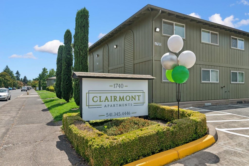 A sign for Clairmont Apartments is in front of a building.