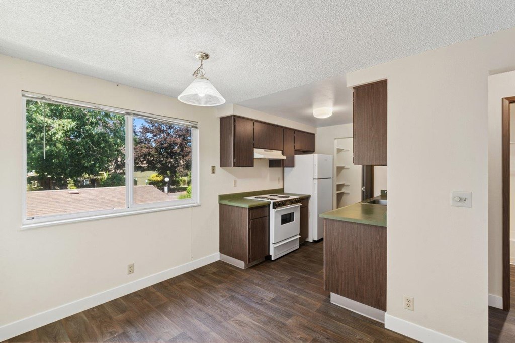 A kitchen with white appliances and brown cabinets.