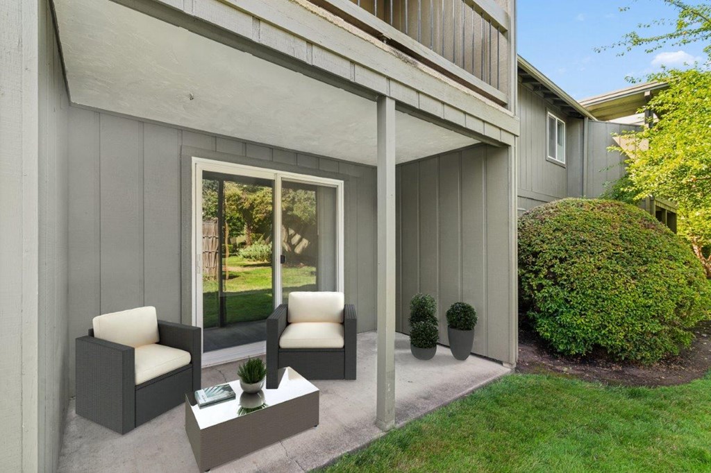 A grey house with a white chair and table outside.
