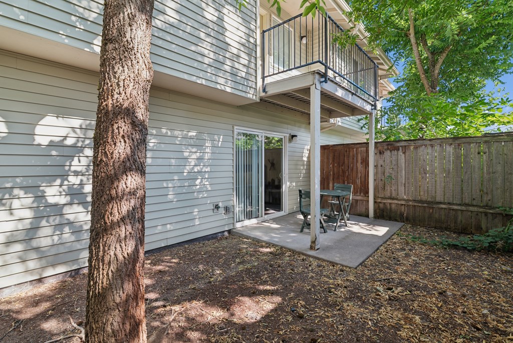 A tree stands in front of a house with a deck.