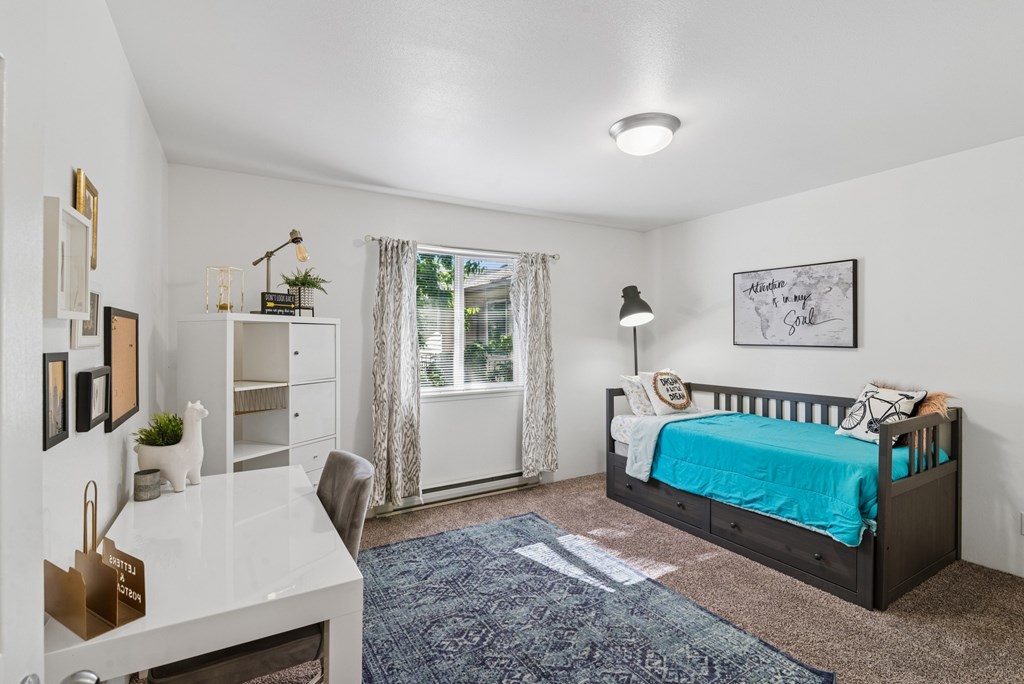 A bedroom with a bed, desk, and chair.