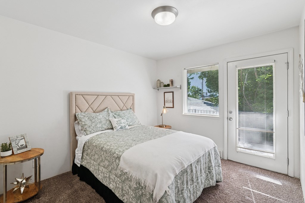 A bedroom with a bed, nightstand, and window.