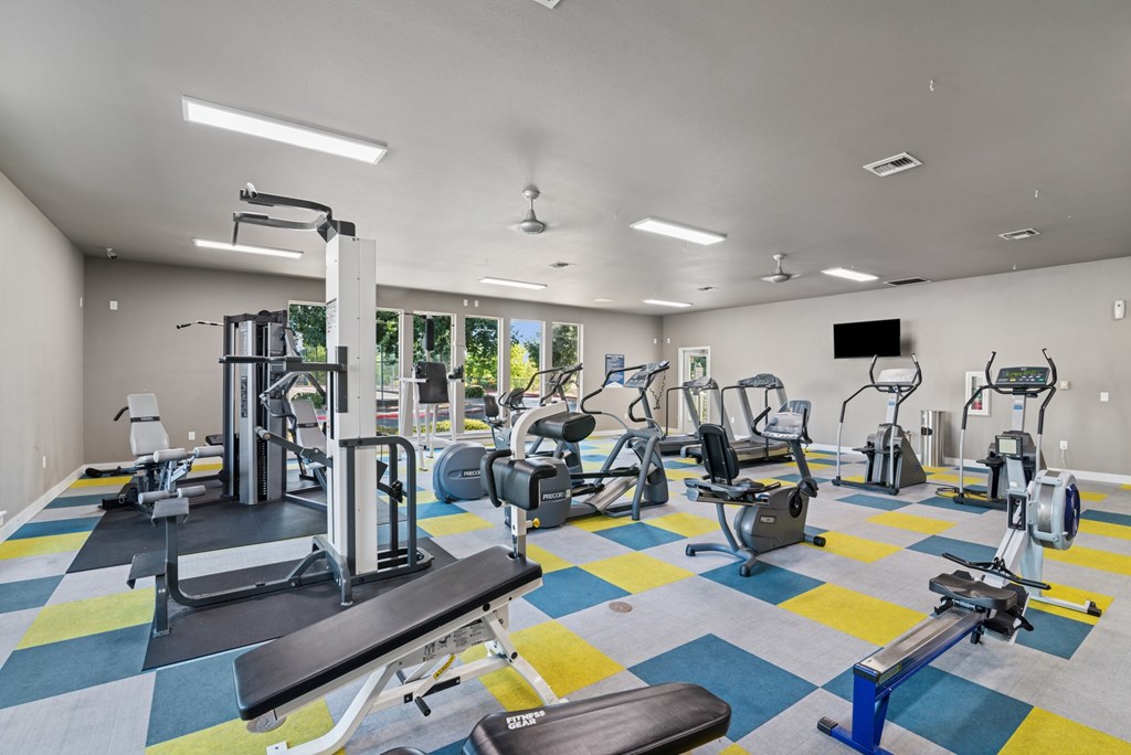 A gym with a variety of equipment including treadmills, weights, and exercise machines.