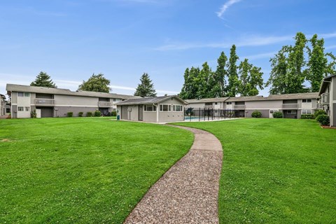 A grassy area with a concrete walkway leading to a building.