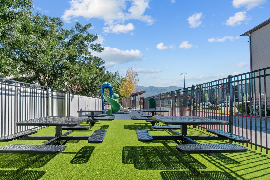 a picnic area with picnic tables and a slide on a sunny day