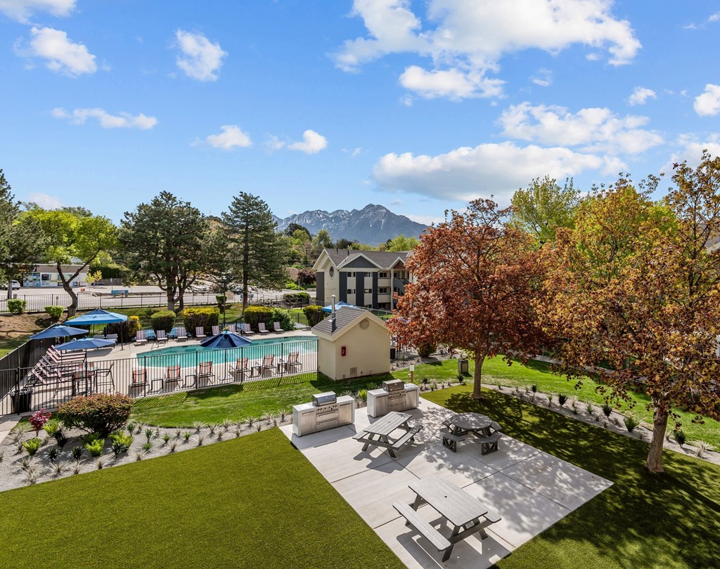 A backyard with a picnic table, a pool, and a mountain in the background.