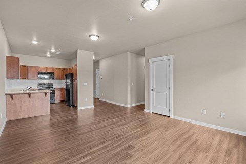 an empty living room and kitchen with wood flooring