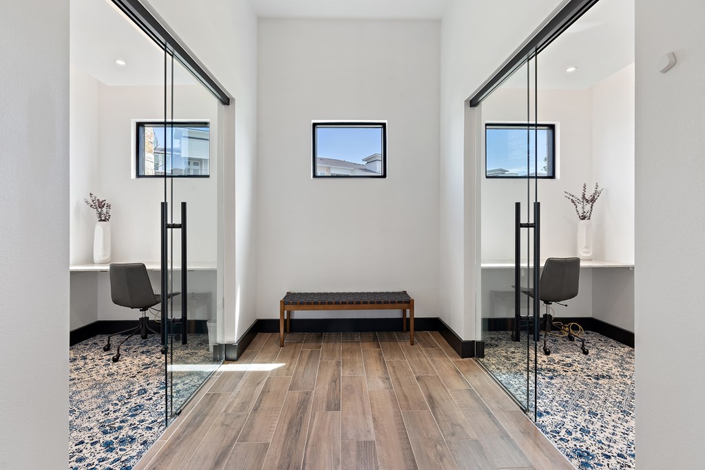 A hallway with a bench, chairs, and mirrors.
