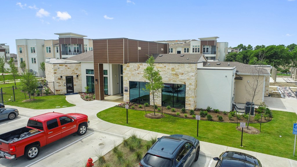 A red pickup truck is parked in front of a building with a stone facade.