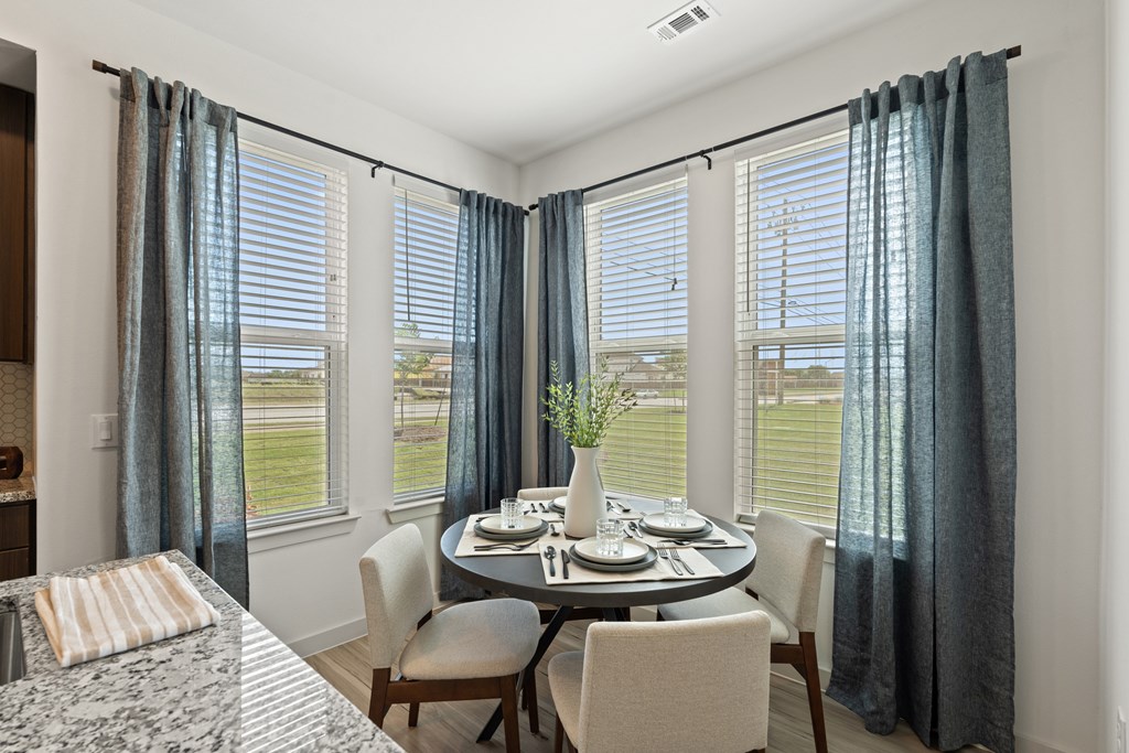 A dining room with a table set for two and a view of the outdoors.