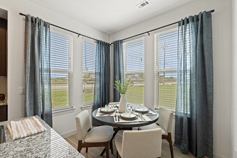 A dining room with a table set for two and a view of the outdoors.