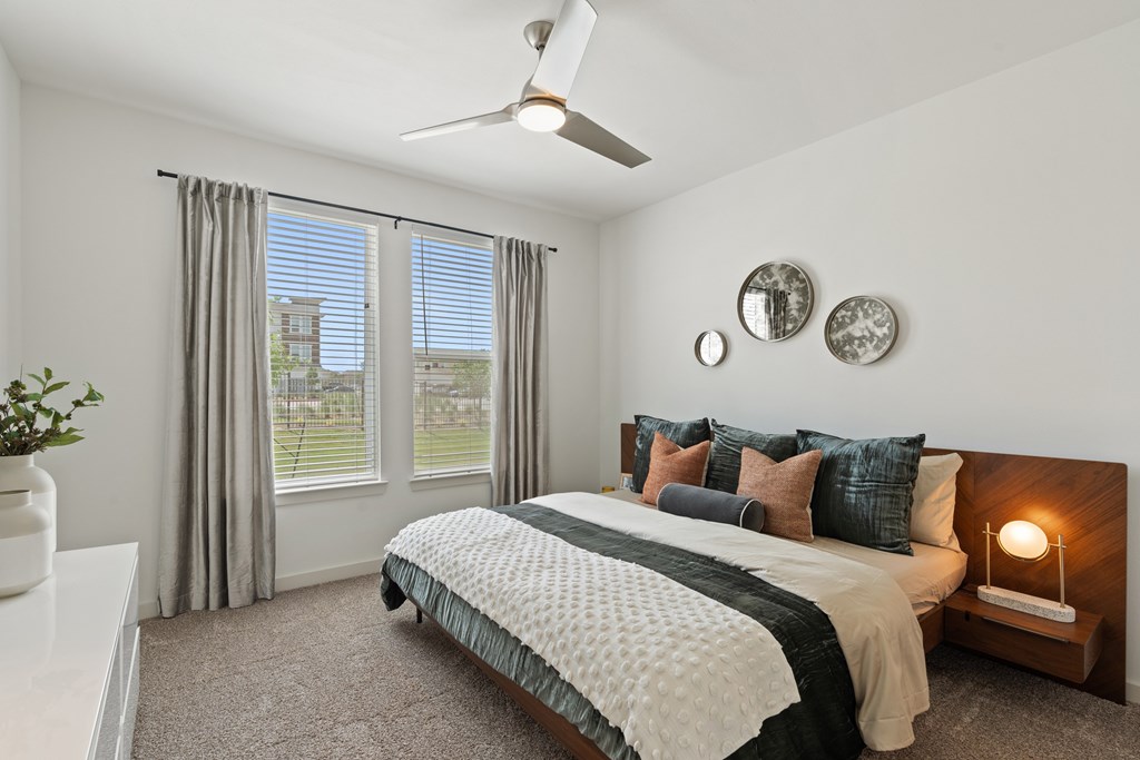A bedroom with a large bed and a ceiling fan.