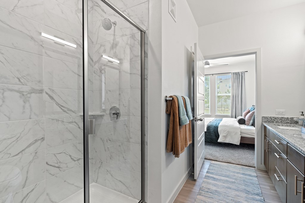 A bathroom with a walk-in shower and a marble floor.