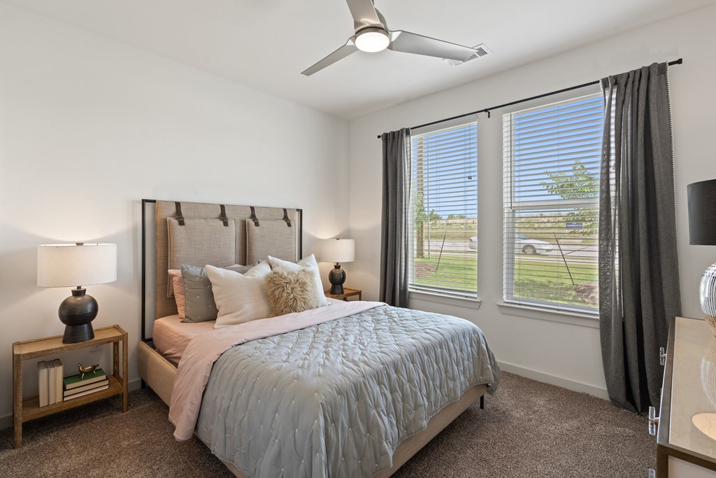 A bedroom with a large bed and a ceiling fan.