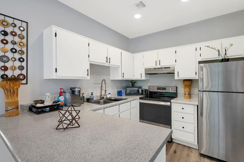 A kitchen with white cabinets and a stainless steel refrigerator.