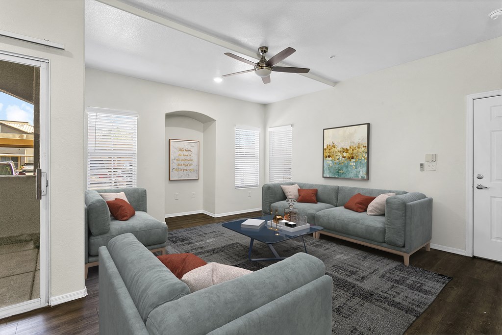 a living room with couches and a ceiling fan