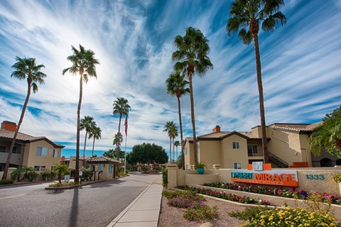 A street view of a residential area with palm trees and houses.