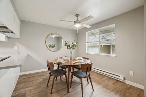 A dining room with a round mirror and a table set for four.