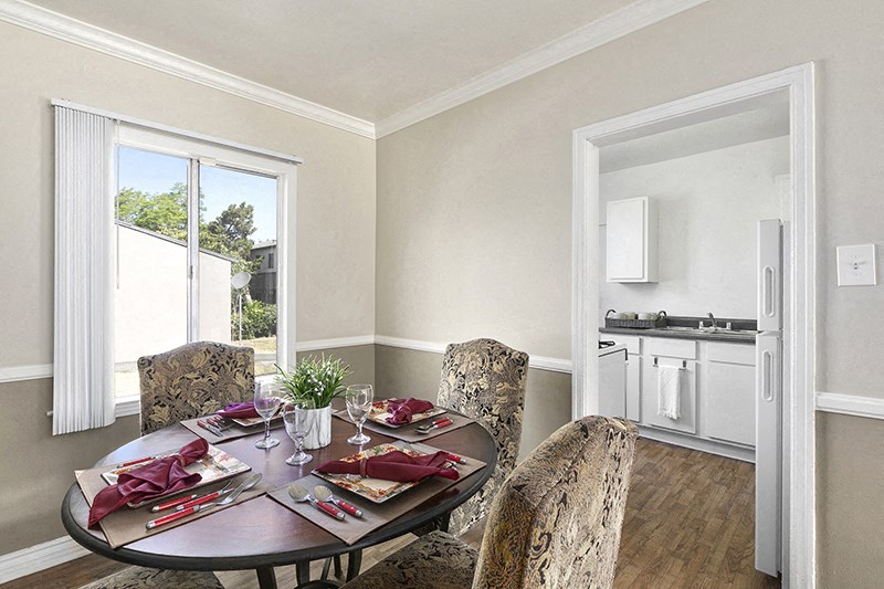 a dining room with a table and chairs and a kitchen in the background