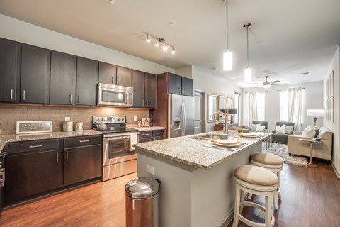 A modern kitchen with dark wood cabinets and stainless steel appliances.