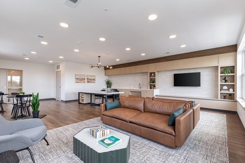 A living room with a brown leather couch and a grey armchair.