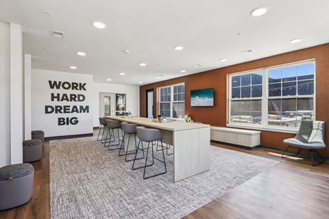 A modern office space with a long table and chairs, a carpeted floor, and a motivational message on the wall.