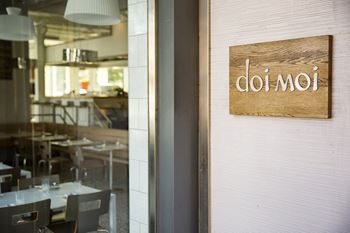 a sign on the door of a restaurant with tables and chairs