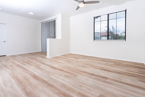 A room with a ceiling fan and a window with blinds.